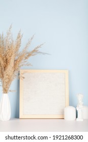 Dried pampas grass in vases, small statue, candles and felt letter board on white and blue background, interior, home design. Art concept. copy space