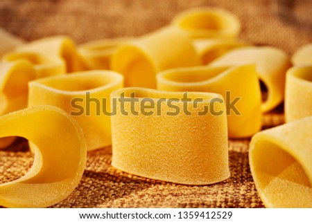 Dried pasta calamarata on a brown cloth , Neapolitan thick and short pasta ,