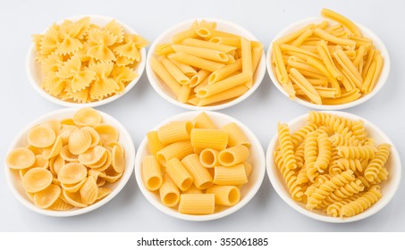 Dried pasta variety in shapes in white bowl over white background - Shutterstock ID 355061885