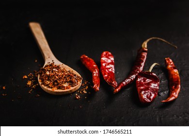 Dried red chili peppers and chili powder spice on black background