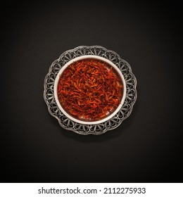 Dried Rich Scarlet Red Threads Stigmas Of Organic Persian Saffron Sargol Spice In Vintage Silver Saucer Dish On Black Background. Pure Iranian Premium Saffron