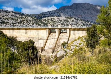 Dried up riverbed in front of the footbridge over the dam of Palma de Mallorca water supply Embassament de Cúber in the valley Torrent d'Aumadrá with the mountain Penyal des Migdia in the background.