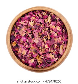 Dried Rose Petals In A Wooden Bowl On White Background. Used For Perfumes, Cosmetics, Teas And Baths. Purple Colored Organic Herb. Isolated Macro Photo Close Up From Above.