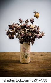 dried rose in vase on wooden table