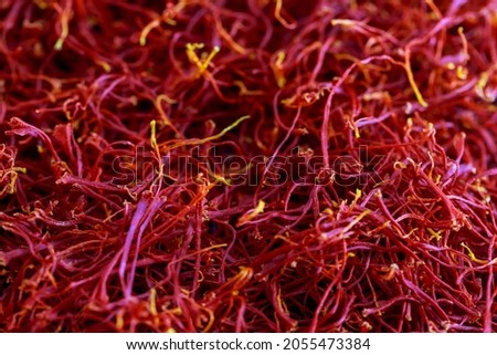 Dried saffron threads are scattered on the table. Background from red saffron stamens. The spice is ready to eat.