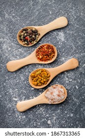 Dried Seasoning Herbs Spices Chili Flakes, Pepper, Turmeric And Salt Crystals In Wooden Spoons Overhead Vibrant Color Arrangement On Rustic Gray Wooden Table Background Studio Shot