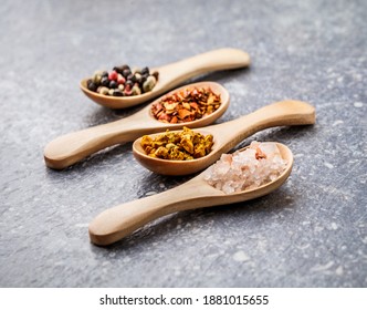 Dried Seasoning Herbs Spices Chili Flakes, Pepper, Turmeric And Salt Crystals In Wooden Spoons Overhead Vibrant Color Arrangement On Rustic Gray Wooden Table Background Studio Shot