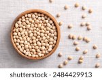 Dried soybeans, also soy beans or soya beans in a wooden bowl on linen fabric. Whole and raw seeds of the legume and oilseed Glycine max, with a very high protein and oil content. Close-up from above.