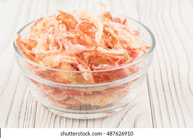 Dried squid in a glass bowl on old wooden table. Selective focus.