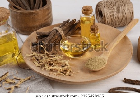 Dried sticks of licorice roots, powder and essential oil on white wooden table Imagine de stoc © 