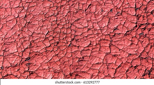 Dried in the sun and cracked red paint on the wall of a village house 