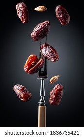 Dried Sweet Dates On A Fork, Black Background.