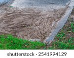 Dried traces of mud flows of earth washed from the green spaces of the park onto the surface of asphalt, as a result of sudden flooding by a huge amount of water due to a downpour or burst water pipe.