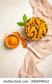 Dried turmeric roots and powder with leaves on a light background