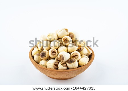 Dried white lotus seeds in a saucer on white background	
