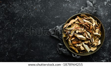 dried wild organic porcini mushroom on a black stone background. Autumn food. Top view. Free space for text.