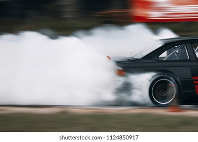 Drift car in the motion drives fast with a lot of smoke. Car wheel spinning 