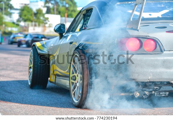 Drift car\
standing at the start line, waiting for race to begin. Rally car\
warming up the tires, blue smoke all\
around
