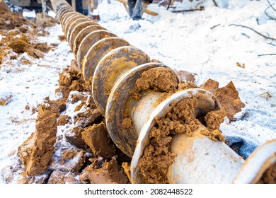 a drill auger is lying on the snow in the clay after deep exploration of the frozen soil, selective focus