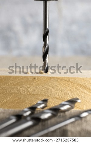 A drill bit being screwed into wood