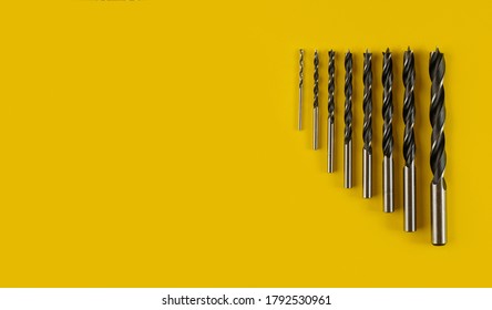 Drill bits of different sizes on yellow background,top view.Drills for wood of different sizes for a drill on an yellow background. Construction tool