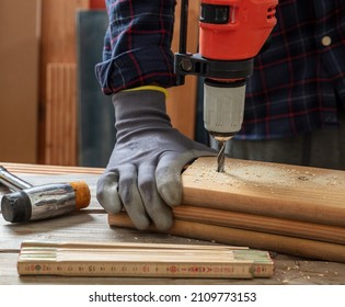 Drill Electric Tool, Gloved Hand Drilling Wood. Construction Industry, Carpenter Work Bench Table Closeup View