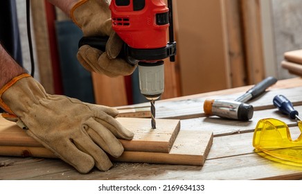 Drill Electric Tool, Gloved Hand Drilling Wood. Construction Industry, Carpenter Work Bench Table Closeup View