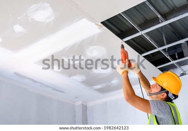 Drill home ceiling Construction workers\
assemble the ceiling with drywall and attach the drywall to the\
ceiling metal frame with a\
screwdriver.