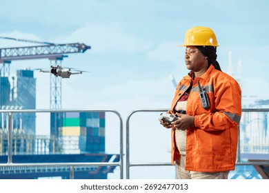 Drilling barge engineer using drone to access areas that pose safety risks to humans from safe distance. Woman on offshore platform deck uses remote control UAV to conduct aerial inspection