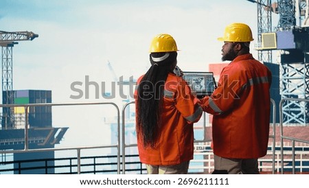 Drilling barge engineering team on deck studying geological maps to locate fossil fuel deposits. Offshore platform teamworking colleagues perform site assessment using digital mapping tech,