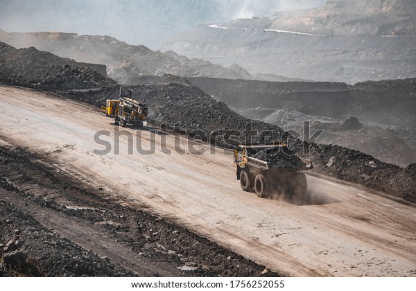 Drilling car and big yellow\
mining empty truck with dust transportation. Open pit mine\
industry.