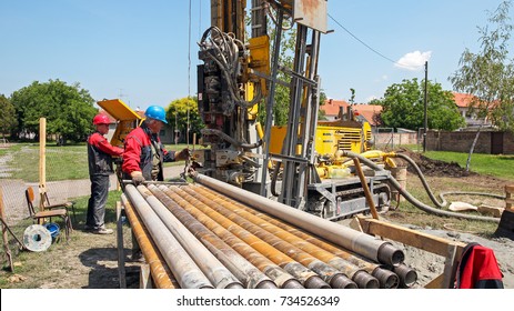 Drilling Geothermal Well.  Workers On Drilling Rig. A Worker Prepares To Join Two Pieces Of Drill Pipe On A Drilling Rig. Drilling Geothermal Well For A Residential Geothermal Heat Pump.