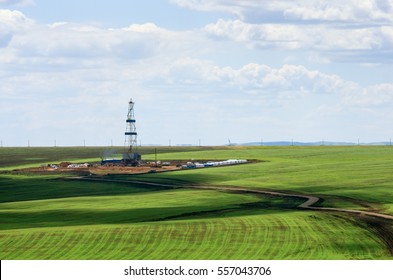 Drilling rig among agricultural fields. View from above