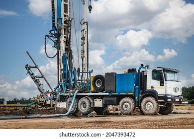 The Drilling Rig Close-up Is Drilling A Well Against The Background Of The Cloudy Sky. Deep Hole Drilling. Geological Exploration Work. Mineral Exploration. Powerful Drill Drills A Well