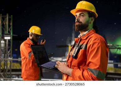 Drilling rig engineer analyzing derrick performance on digital dashboard screen. Offshore platform employee monitoring oil extraction rates and system pressure using laptop software