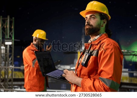 Drilling rig engineer analyzing derrick performance on digital dashboard screen. Offshore platform employee monitoring oil extraction rates and system pressure using laptop software