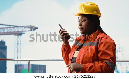Drilling rig worker using walkie talkie enabling quick response coordination, performing maintenance. Engineer listens to status report through handheld radio, managing logistics