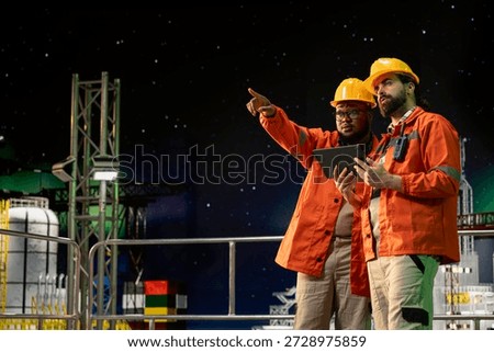 Drilling ship engineers using tablet to control subsea systems during night shift. Coworkers monitoring anomaly detection using device on offshore fossil fuel extraction platform