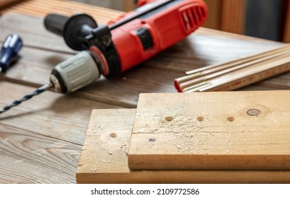 Drilling Wood. Electric Drill Tool And Planks On Carpenter Work Bench Table Closeup View Construction Industry,