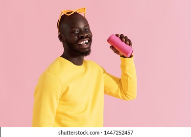 Drink. Colorful Portrait Of Happy Black Man Drinking Soft Drink On Pink Background. Cheerful Smiling Young African American Male Model In Yellow Fashion Clothes Holding Pink Soda Can In Studio 