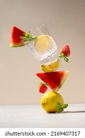 Drink levitation wiht watermelon, lemon, strawberry and fresh mint flying with detox fruit water glass. Abstract healthy food concept.