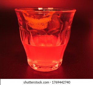 A Drink With A Lipstick Mark On The Glass. Red Light And Dark Background. 