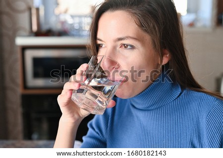 Drink plenty of water from the virus, Covid-19 Pandemic Coronavirus. Girl drinks water from a glass