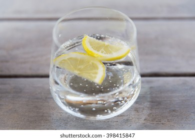 Drink And Refreshment Concept - Glass Of Sparkling Water With Lemon Slices On Table