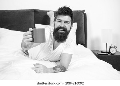 Drink with relish. Happy hipster offer hot cup. Pleasure of coffee. Bearded man give cup of coffee. Enjoying cup of pleasure. Pleasure and joy. Pure pleasure. Enjoy yourself. Good morning