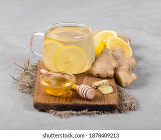 Drink tea lemon ginger with honey in a cup on a wooden board on a light gray background - Shutterstock ID 1878409213