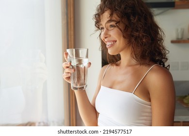 Drink Water. Happy Young Woman With Glass Of Fresh Water In White Kitchen Portrait. Beautiful Smiling Girl drinking Pure Mineral Water In Morning At Home  - Powered by Shutterstock