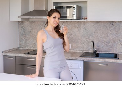 Drink Water. Happy Young Woman With Glass Of Fresh Water In Kitchen Portrait. Beautiful Smiling Caucasian Girl Drinking Pure Mineral Water In The Morning At Home