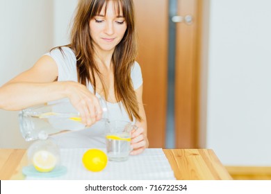 Drink water. Woman's hand pouring fresh pure water with pieces of lemon from pitcher into glass in the morning Health and diet concept. Healthy lifestyle. Health care and beauty. Hydration.