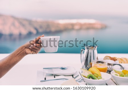 Drinking coffee cup at breakfast brunch table of cruise ship restaurant - luxury travel vacation getaway in Santorini - honeymoon destination.